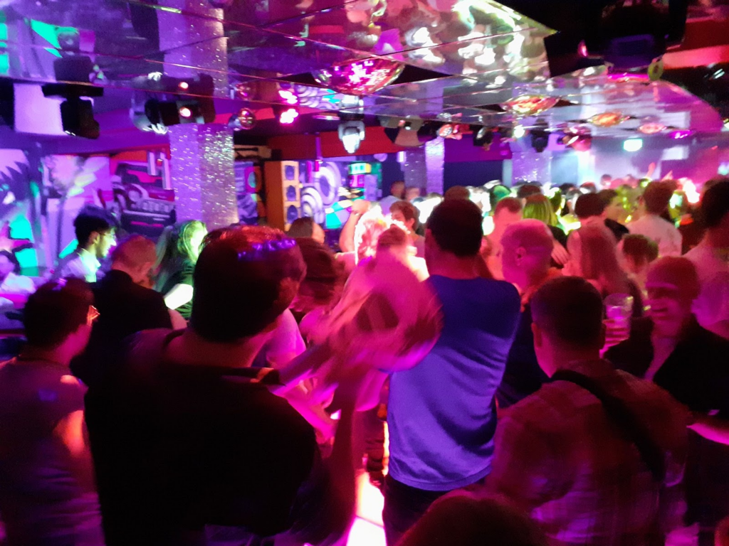 A gorup of people in a colourfully lit-up night club